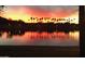 Beautiful sunset reflected in the lake, lined with palm trees and street lights under a colorful sky at 10952 S Desert Lake Dr, Goodyear, AZ 85338