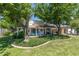 Beautiful front yard featuring mature trees, lush landscaping, and a cozy covered porch at 1306 W Heatherbrae Dr, Phoenix, AZ 85013