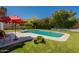 Inviting pool with lush landscaping and a red umbrella creating a serene backyard oasis at 14624 N 44Th St, Phoenix, AZ 85032