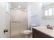 Bathroom includes a shower with glass doors, vanity with a dark wood cabinet, toilet, and window at 1550 W Willow Ave, Phoenix, AZ 85029