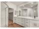 Bright bathroom with a large mirror, double sinks, white cabinets, wood floors, and glass shower at 2019 E Campbell Ave # 110, Phoenix, AZ 85016