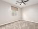 A neutral bedroom offers soft carpeting, natural lighting from the window, and dark-colored ceiling fan at 21408 S 224Th Pl, Queen Creek, AZ 85142