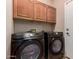Functional laundry room with wood cabinets and front load washer and dryer at 2315 W Beverly Rd, Phoenix, AZ 85041