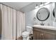 This bathroom features a wood vanity, decorative mirror, and a white shower curtain at 2924 W Anderson Dr, Phoenix, AZ 85053