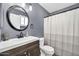Well-lit bathroom featuring a dark wood vanity, round mirror, and shower-tub combo at 2924 W Anderson Dr, Phoenix, AZ 85053