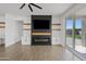 Modern living room with sleek fireplace, wood-look floors, and sliding glass doors to the backyard at 486 E Bamboo Ln, San Tan Valley, AZ 85140