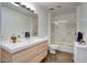 Bright bathroom featuring a large mirror, modern vanity, and a shower-tub combination with glass doors at 609 E Royal Palm S Sq, Phoenix, AZ 85020