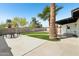Inviting backyard featuring an open patio, lush lawn, a fire pit, and tall palm trees at 653 W Inglewood St, Mesa, AZ 85201