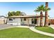 A covered patio, artificial turf, and mature palm trees create a relaxing backyard space at 653 W Inglewood St, Mesa, AZ 85201