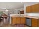 Cozy kitchen featuring wood cabinets, a stainless steel dishwasher, and a view of an open dining area at 8237 W Alex Ave, Peoria, AZ 85382