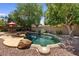 Serene backyard oasis with a freeform pool surrounded by lush trees and ample space for relaxation and entertainment at 8237 W Alex Ave, Peoria, AZ 85382