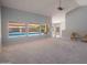 Large living room showcasing carpeted floors, three large rear windows with views of the pool, and light gray walls at 8765 W Custer Ln, Peoria, AZ 85381