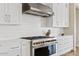 Modern kitchen with stainless steel range, custom hood and white cabinets at 10520 E Thorite Cir, Mesa, AZ 85212