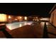 Night view of a well-lit pool with water feature, hot tub, pergola with lounge chairs, and brick paver patio at 10520 E Thorite Cir, Mesa, AZ 85212