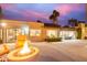 Expansive backyard featuring an outdoor fire pit, orange chairs, lush greenery, and seamless transitions from indoor to outdoor spaces at 10658 E Cinnabar Ave, Scottsdale, AZ 85258