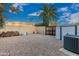 Gravel side yard featuring a wooden gate, AC unit, pile of firewood and mature landscaping at 10658 E Cinnabar Ave, Scottsdale, AZ 85258