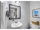 Cozy powder room boasts modern fixtures, framed mirror, and a basket for essentials at 12107 N 66Th Ave, Glendale, AZ 85304