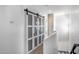Hallway features neutral carpet, white walls, and a charming sliding barn door to a bedroom at 12107 N 66Th Ave, Glendale, AZ 85304