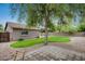 Wide-angle shot showcasing the backyard with a mature tree, large grass lawn and concrete patio at 16103 W Redfield Rd, Surprise, AZ 85379