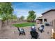 Inviting backyard featuring a fire pit with chairs, grass lawn, desert landscaping and a privacy fence at 16103 W Redfield Rd, Surprise, AZ 85379
