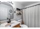 A well-lit bathroom with a stylish vanity, decorative mirror, and a shower featuring a neutral-toned curtain at 16103 W Redfield Rd, Surprise, AZ 85379
