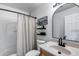 Bright, clean bathroom featuring a shower with curtain, single sink vanity and black framed round mirror at 16103 W Redfield Rd, Surprise, AZ 85379