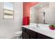 Well-lit bathroom with a white sink, a dark brown vanity and a coral accent wall at 17532 W Copper Ridge Dr, Goodyear, AZ 85338