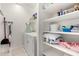 Brightly lit laundry room with washer, dryer, cleaning supplies, and built-in shelving at 17532 W Copper Ridge Dr, Goodyear, AZ 85338