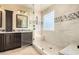 Bathroom showing a glass-enclosed shower with seat, dual sink vanity, and tile floors at 18171 W Marshall Ln, Surprise, AZ 85388