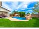 Backyard oasis featuring sparkling pool with rock waterfall, cozy cabana, and lush landscaping at 18171 W Marshall Ln, Surprise, AZ 85388