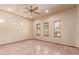 A naturally lit bedroom features tan tiled flooring, a ceiling fan, and three windows with wooden frames at 1954 N Calle Maderas --, Mesa, AZ 85213