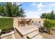 Charming back patio area with a high-top table, manicured bushes, and concrete pavers at 20426 N Blazing Sun Rd, Maricopa, AZ 85138