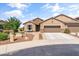 A tan home features a three-car garage, desert landscaping, and a cozy front patio with seating at 20426 N Blazing Sun Rd, Maricopa, AZ 85138