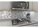 Close up of the kitchen with gas cooktop, stainless steel microwave and designer tile backsplash at 20426 N Blazing Sun Rd, Maricopa, AZ 85138