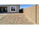 An empty backyard ready for landscaping, featuring a block wall and sliding glass doors to the home at 22709 E Saddle Way, Queen Creek, AZ 85142