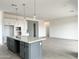 A kitchen features white cabinetry, a dark gray island with quartz countertops, and stainless pendant lighting at 22709 E Saddle Way, Queen Creek, AZ 85142