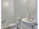 This modern half-bathroom features an elegant pedestal sink, contemporary fixtures, and a stylish round mirror at 22709 E Saddle Way, Queen Creek, AZ 85142