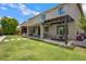 Rear elevation featuring a covered patio, an outdoor dining area, and a grassy backyard at 2496 E Lindrick Dr, Gilbert, AZ 85298