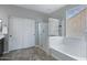 Bright bathroom featuring a walk-in shower, a soaking tub, and a sliding door closet at 2496 E Lindrick Dr, Gilbert, AZ 85298