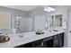 Bright bathroom featuring double sinks, a large mirror, and a walk-in shower with glass doors at 2496 E Lindrick Dr, Gilbert, AZ 85298