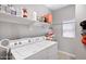 Bright laundry area with a washing machine, dryer, a storage shelf, and a window for added convenience at 2496 E Lindrick Dr, Gilbert, AZ 85298