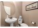 Neat half bathroom featuring pedestal sink, round mirror, and framed wall art at 2607 W Gray Wolf Trl, Phoenix, AZ 85085
