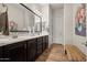 Bathroom featuring double sink vanity, large mirror, and wood look floors at 27276 N 81St Ln, Peoria, AZ 85383