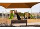 Community playground with climbing structures, slides, and a shaded bench, perfect for to play at 3752 E Terrel St, San Tan Valley, AZ 85143