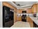 A cozy kitchen featuring wood cabinetry, granite countertops, and modern black appliances at 40061 W Novak Ln, Maricopa, AZ 85138