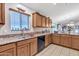 An airy kitchen with granite countertops, a stainless steel sink, and wood cabinets at 40061 W Novak Ln, Maricopa, AZ 85138