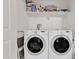 Bright laundry room with side-by-side washer and dryer and a storage shelf at 40061 W Novak Ln, Maricopa, AZ 85138