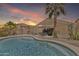 A beautiful backyard featuring a sparkling pool, patio seating, and lush desert landscaping at 40061 W Novak Ln, Maricopa, AZ 85138