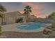 A beautiful backyard featuring a sparkling pool, patio seating, and lush desert landscaping at 40061 W Novak Ln, Maricopa, AZ 85138