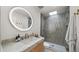 Modern bathroom with glass shower, updated vanity, and round mirror with soft, ambient lighting at 4411 N 40Th St # 40, Phoenix, AZ 85018